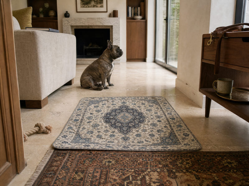 A Proper Pet washable pee pad on the floor of a furnished living room, reading as a small rug beside an armchair