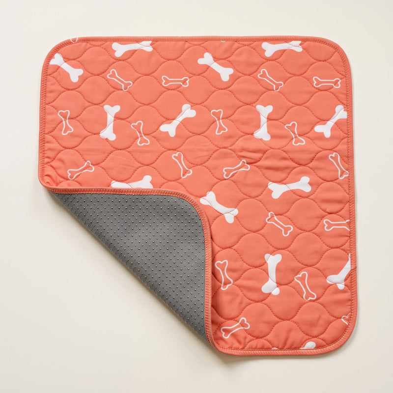 Orange Bones washable pee pad, one corner turned back to show the silicone-dot underside